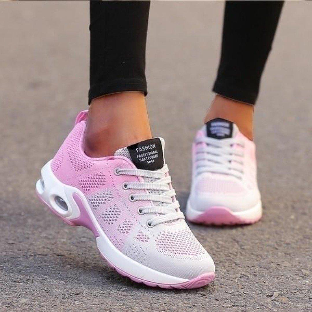 Chaussures de sport rose et blanc pour femme, semelle épaisse, design moderne, idéales pour la course et le fitness, portées sur trottoir.