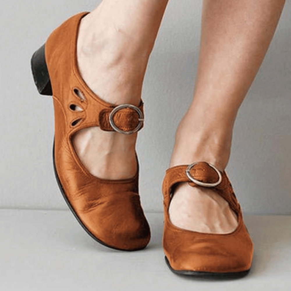 Chaussures marron en cuir pour femme avec boucle argentée, talon bas et détails découpés. Confort et style élégant pour toutes occasions.