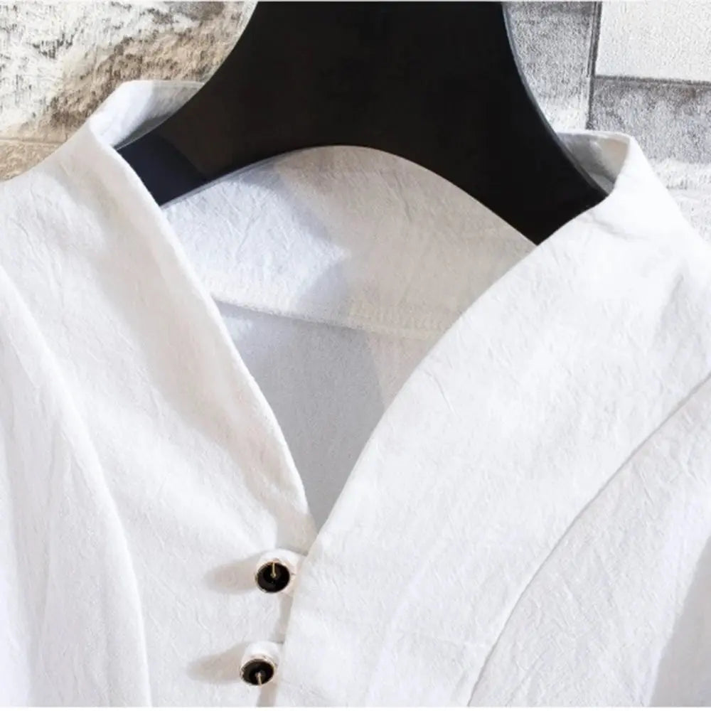 Chemise blanche en lin sur cintre noir, col en V, boutons noirs, texture légère. Mode élégante, vêtement décontracté, style minimaliste.