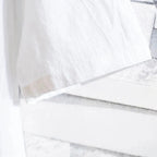 Manche de chemise blanche en coton, texture légère et élégante, sur fond de mur en briques blanches. Mode minimaliste, style épuré.