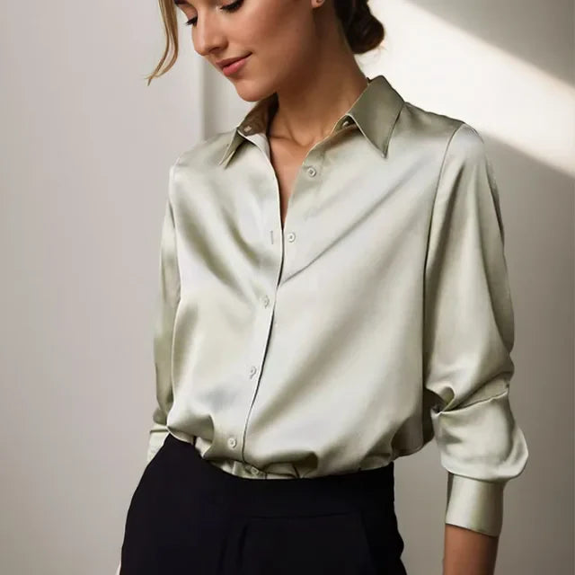 Femme portant une chemise en satin beige élégante, manches longues, col classique, associée à un pantalon noir. Mode féminine chic et moderne.