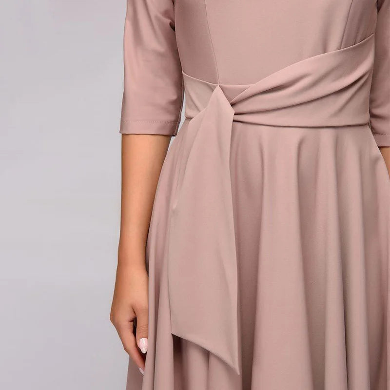 Robe élégante beige avec manches mi-longues et ceinture nouée, style chic et moderne, mode féminine tendance, tenue de soirée raffinée.