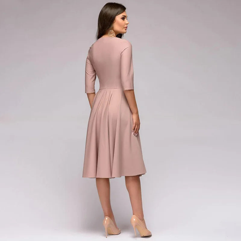 Femme portant une robe rose pâle élégante, manches trois-quarts, vue de dos, talons beiges. Mode féminine chic, tenue de soirée.