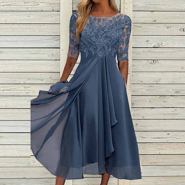 Robe élégante bleu marine en dentelle avec manches trois-quarts, jupe fluide, fond en bois clair. Mode féminine, tenue de soirée chic.
