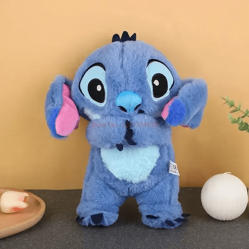 Peluche Stitch bleue debout sur une table, oreilles roses, fond beige, décoration minimaliste. Jouet Disney populaire, cadeau enfant.