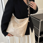 Sac à main en cuir beige porté par une femme en veste noire. Accessoire élégant avec bandoulière décorative, idéal pour la mode urbaine chic.