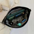 Sac à main ouvert avec livre, tablette, téléphone, parapluie, et flacon. Accessoires de mode, organisation, style élégant.