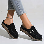 Chaussures mocassins noirs pour femmes avec boucle, semelle en liège, portées avec un jean. Mode décontractée, tendance chaussures automne.