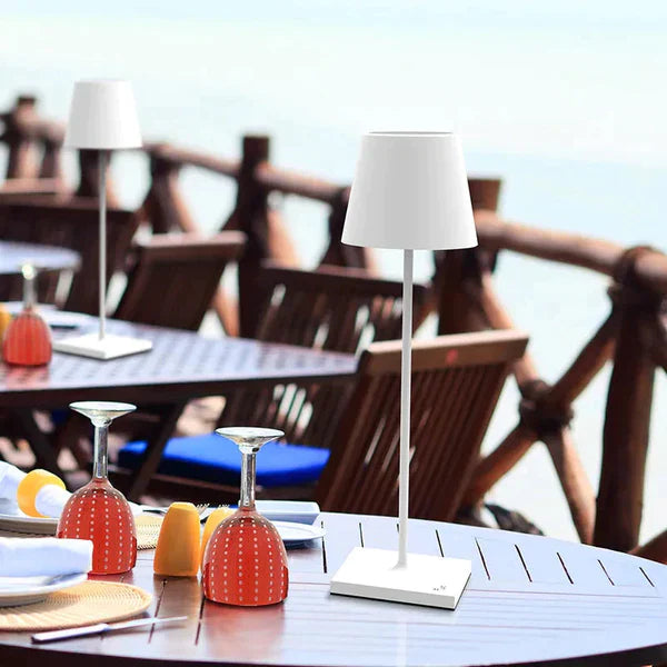 Lampe de table blanche moderne sur une terrasse en bois, vue sur la mer. Design élégant, idéal pour l'éclairage extérieur et la décoration de jardin.