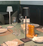 Table élégamment dressée avec lampes modernes, verres à vin, assiettes blanches, serviettes, moulin à poivre et sel, et décoration florale.