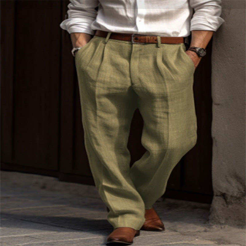 Homme portant un pantalon en lin vert olive, chemise blanche, ceinture marron et chaussures en cuir marron, style élégant et décontracté.