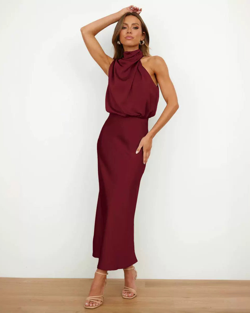 Robe longue bordeaux élégante, sans manches, col drapé, portée par une femme posant debout. Mode féminine chic, tendance soirée.