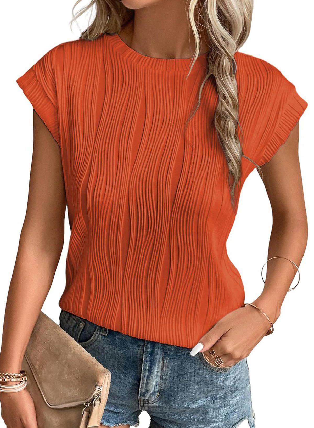 Femme portant un haut plissé orange vif avec manches courtes, associé à un short en jean. Mode estivale, tenue décontractée, style tendance.