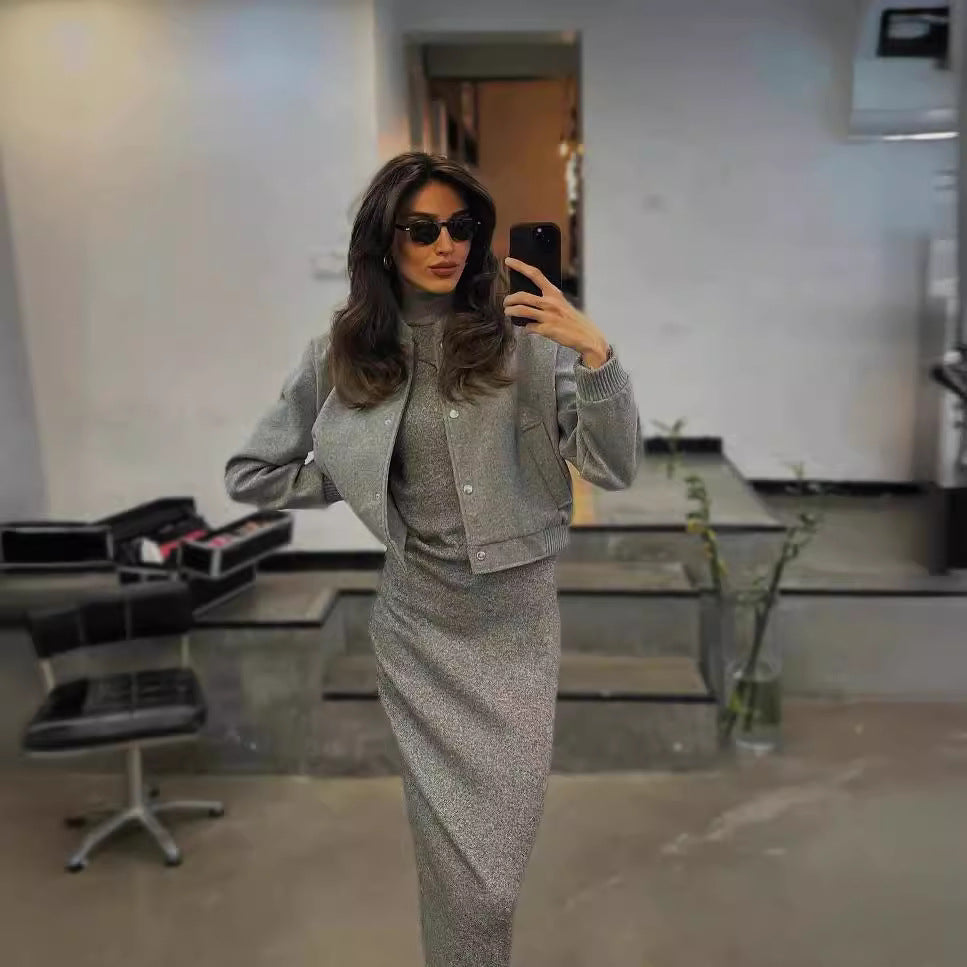 Femme élégante en tenue grise, posant devant un miroir, portant des lunettes de soleil, dans un salon moderne. Mode chic, style urbain.