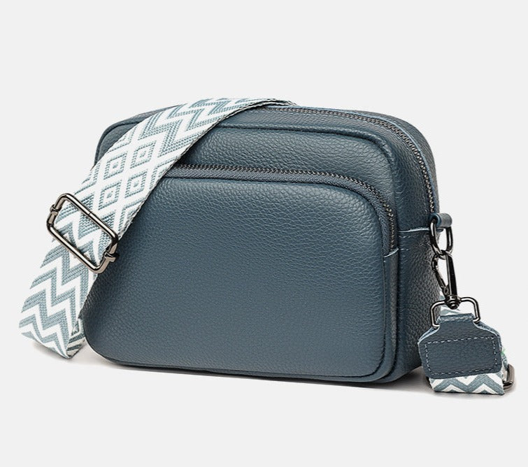 Sac bandoulière en cuir bleu avec sangle à motif géométrique blanc et bleu, design moderne et élégant, idéal pour la mode féminine.
