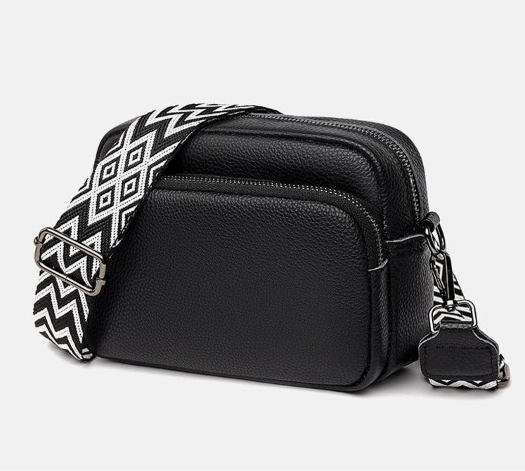 Sac bandoulière noir en cuir avec sangle à motifs géométriques noir et blanc. Accessoire mode tendance, pratique pour un style chic et moderne.
