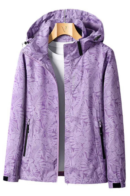 Veste imperméable violette à motifs floraux, capuche ajustable, fermetures éclair noires, accrochée sur un cintre en bois.