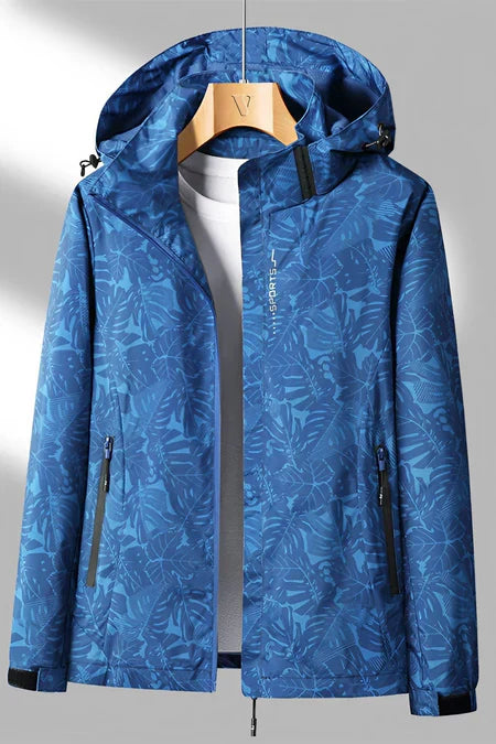 Veste imperméable bleue à motifs floraux, capuche ajustable, fermetures éclair noires, idéale pour randonnée et activités extérieures.