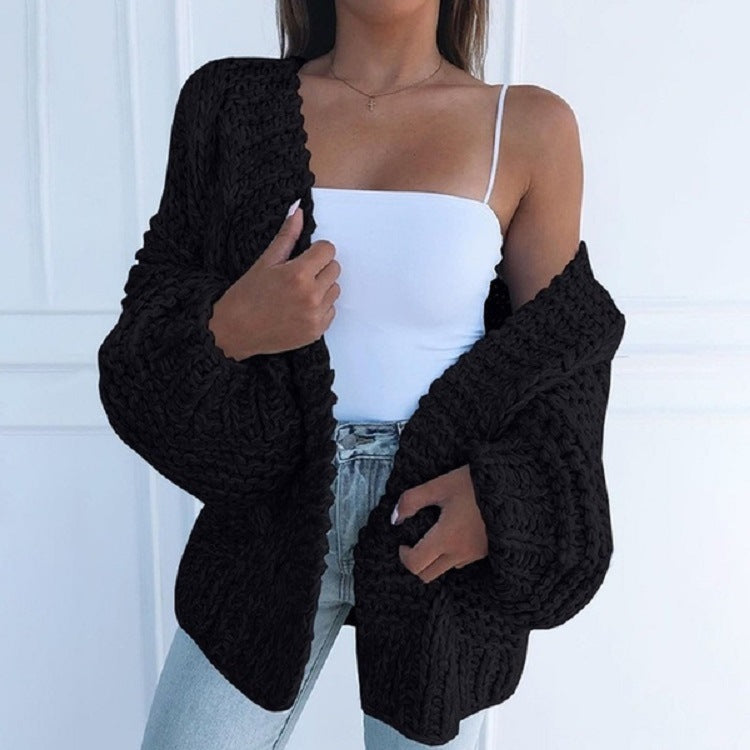 Femme portant un cardigan noir en tricot épais, débardeur blanc et jean bleu clair. Mode automne, style décontracté, tendance féminine.