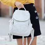 Sac à dos blanc élégant porté par une femme, design moderne avec poches latérales, idéal pour la mode urbaine et les sorties décontractées.