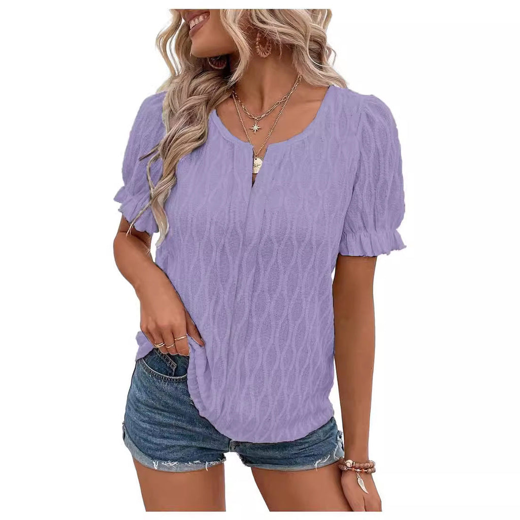Femme portant un haut violet à manches courtes texturées et un short en jean. Style décontracté, mode féminine, tenue estivale tendance.