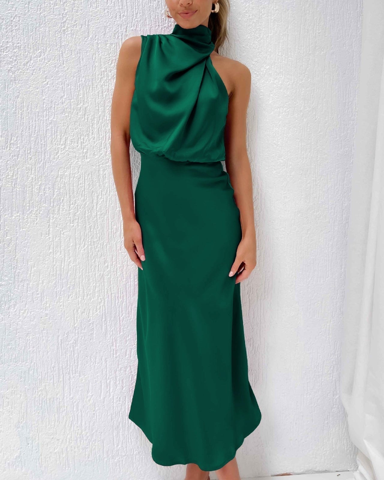 Robe longue verte élégante sans manches, col drapé, portée par une femme sur fond blanc. Mode féminine chic, tenue de soirée sophistiquée.