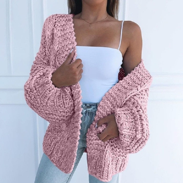 Femme portant un cardigan en tricot rose épais, débardeur blanc et jean clair. Mode automne, style décontracté, tendance vêtements féminins.