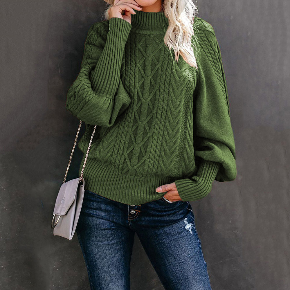 Femme portant un pull vert en maille torsadée avec manches bouffantes, sac à bandoulière gris, et jean décontracté. Mode automne-hiver élégante.