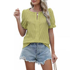 Femme portant un chemisier vert à manches courtes et un short en jean déchiré, style décontracté estival, mode féminine tendance.