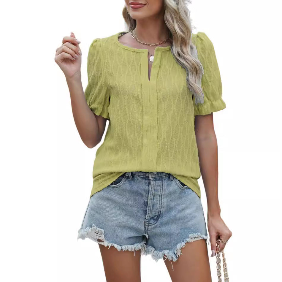 Femme portant un chemisier vert à manches courtes et un short en jean déchiré, style décontracté estival, mode féminine tendance.
