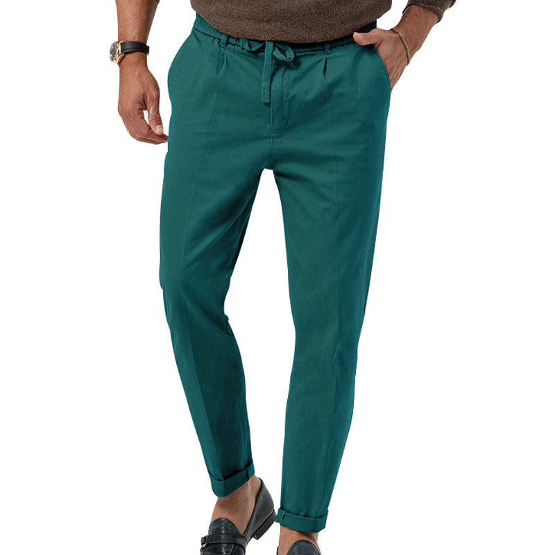 Pantalon vert pour homme, coupe ajustée, avec ceinture à cordon, porté avec des mocassins noirs et un pull marron. Mode masculine élégante.