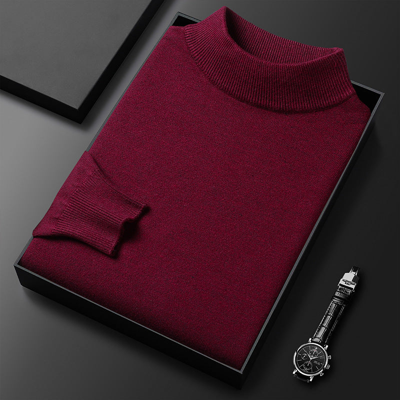 Pull-over bordeaux en laine, col roulé, posé dans une boîte noire, accompagné d'une montre-bracelet élégante sur fond noir. Mode homme chic.