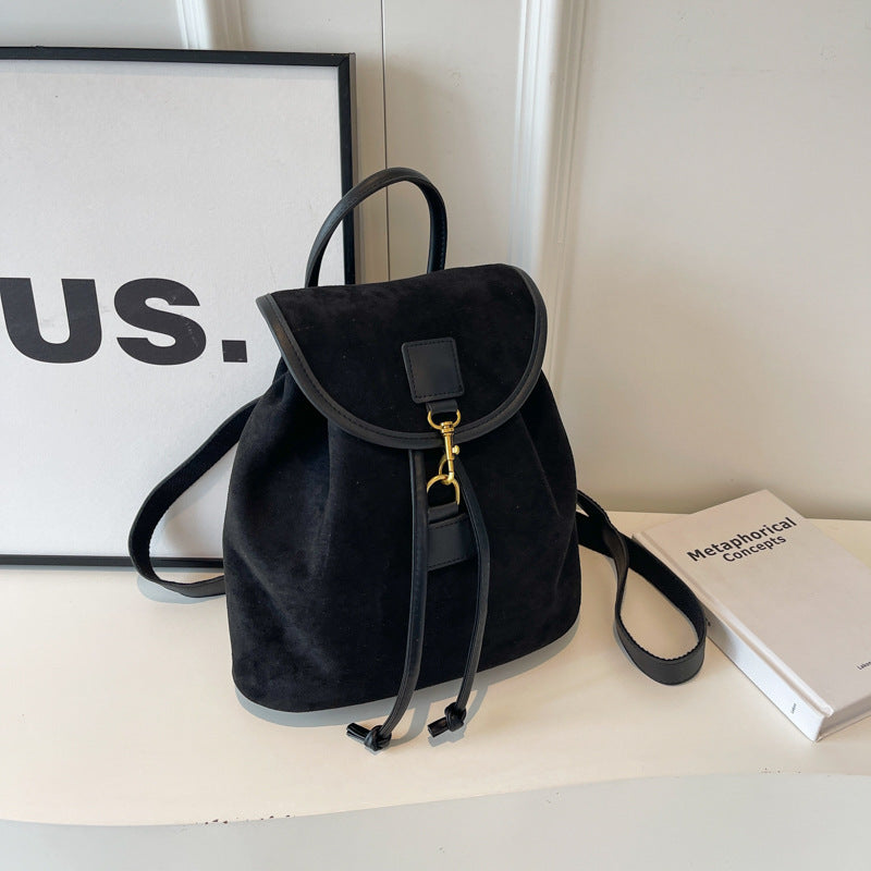 Sac à dos en cuir noir élégant sur une étagère blanche, à côté d'un livre et d'un cadre. Accessoire mode tendance, design minimaliste.