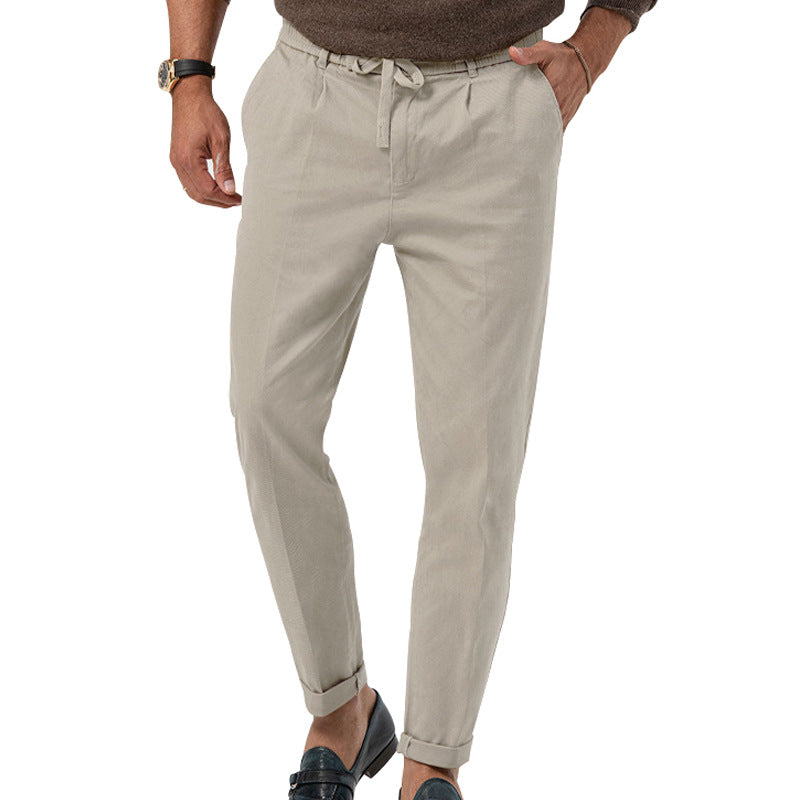 Pantalon chino beige pour homme, coupe ajustée, avec ceinture à cordon, porté avec un pull marron et des mocassins noirs. Mode masculine élégante.