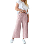 Femme portant un pantalon large rose à rayures, t-shirt blanc et baskets blanches. Mode décontractée, tendance, style estival.