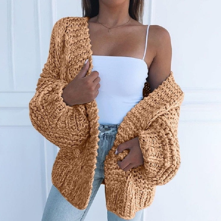 Femme portant un cardigan en maille épaisse beige, débardeur blanc et jean. Mode automne, style décontracté, tendance vêtements chauds.