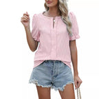 Femme portant un chemisier rose à manches courtes et un short en jean déchiré, style décontracté estival, mode féminine tendance.