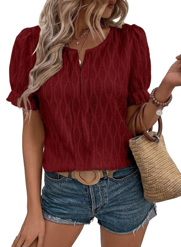 Femme en blouse rouge texturée, manches courtes, portant un short en jean et un sac en paille. Mode estivale décontractée, style chic et tendance.