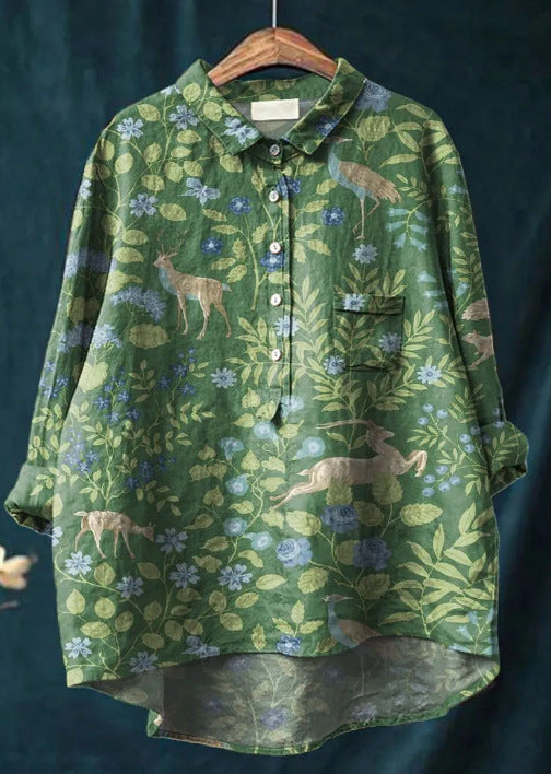 Chemise verte à motifs floraux et animaux, manches longues, col classique, boutons, suspendue sur un cintre en bois. Mode nature, tendance.