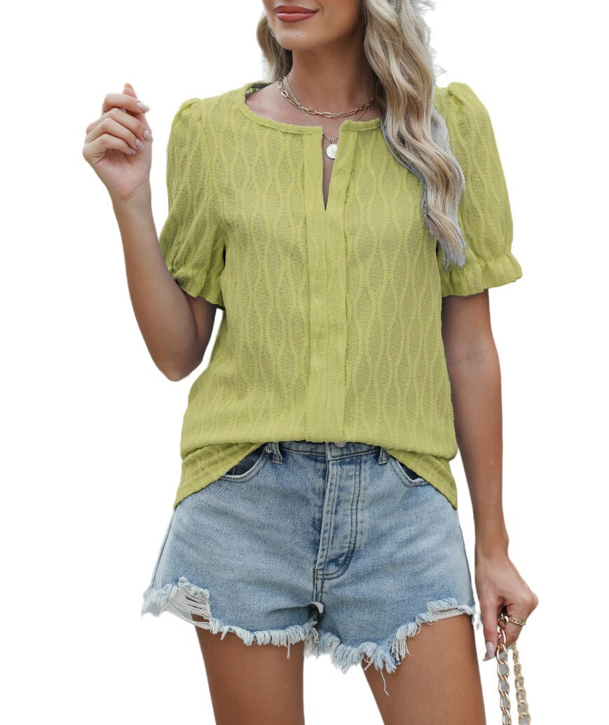 Femme portant un chemisier vert à manches courtes texturées et un short en jean déchiré, style estival décontracté, mode féminine tendance.