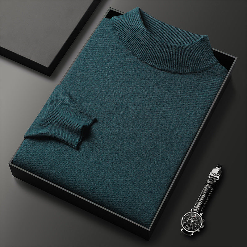 Pull-over en laine vert émeraude plié dans une boîte noire, accompagné d'une montre-bracelet élégante. Mode masculine, vêtements d'hiver.