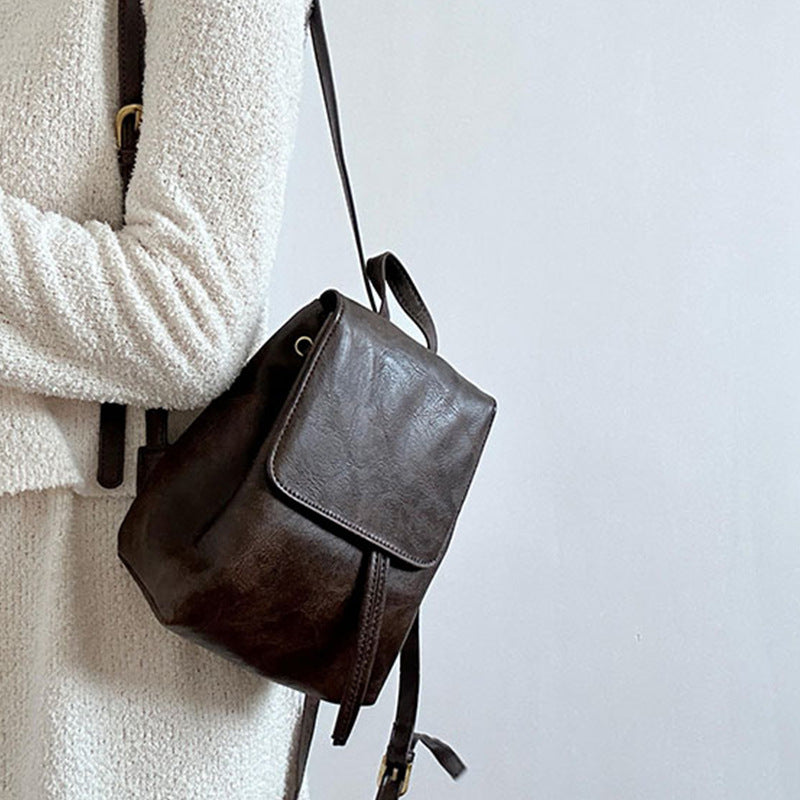 Sac à dos en cuir marron porté par une personne en pull blanc. Accessoire mode élégant, tendance, idéal pour un look chic et décontracté.