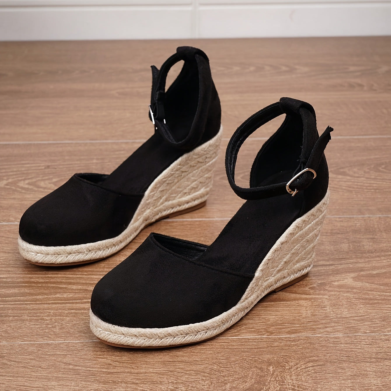 Chaussures espadrilles compensées noires en toile avec semelle en corde, posées sur un sol en bois. Mode féminine, tendance été, confort élégant.