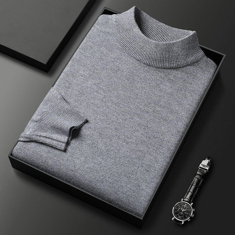 Pull-over gris en laine plié dans une boîte noire, accompagné d'une montre-bracelet élégante sur fond noir. Mode homme, vêtements d'hiver.