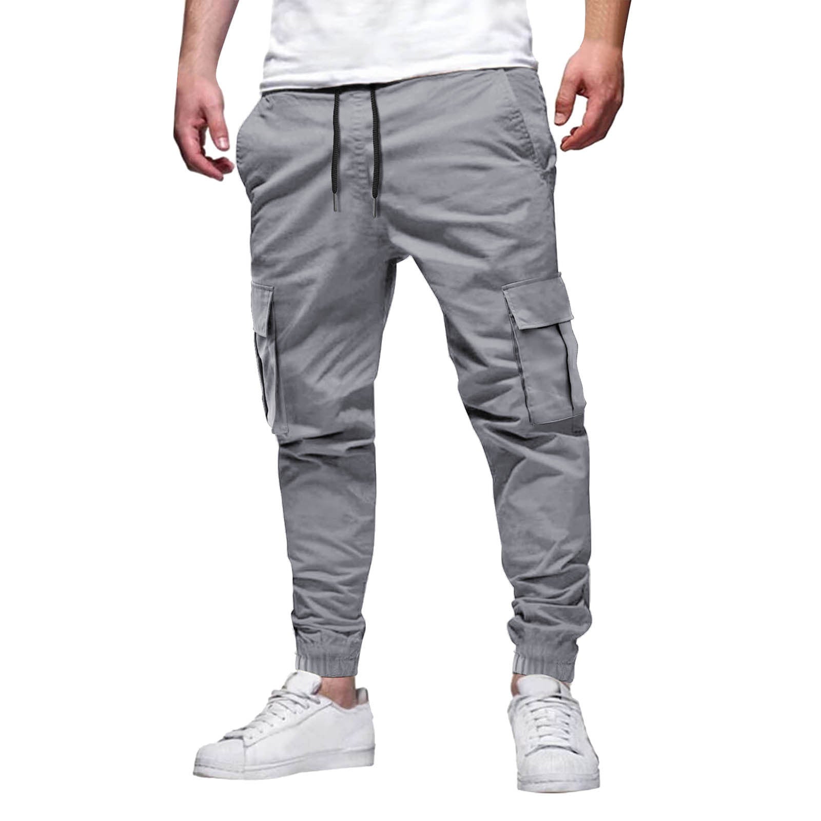 Pantalon cargo gris pour homme avec poches latérales, coupe décontractée, cordon de serrage, porté avec des baskets blanches. Mode urbaine tendance.