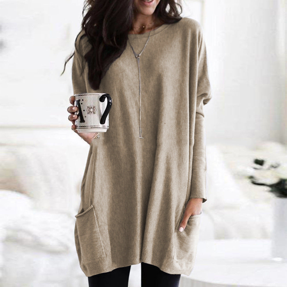 Femme portant un pull beige ample, tenant une tasse de café. Mode décontractée, style automne, intérieur cosy.