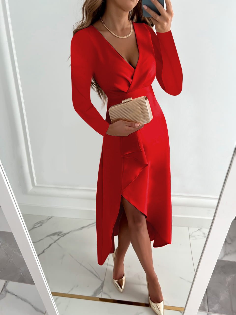 Robe rouge élégante avec décolleté en V, manches longues, fente avant, accessoirisée d'une pochette beige et talons, reflet dans un miroir.