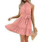 Robe rose sans manches, col haut, ceinture nouée, ourlet volanté, tenue élégante pour femme, accessoirisée d'une pochette beige.