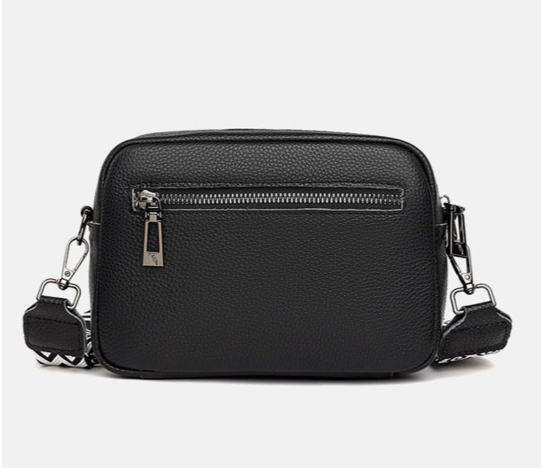 Sac à bandoulière en cuir noir texturé avec fermeture éclair argentée, design moderne et élégant, idéal pour la mode féminine et les accessoires tendance.