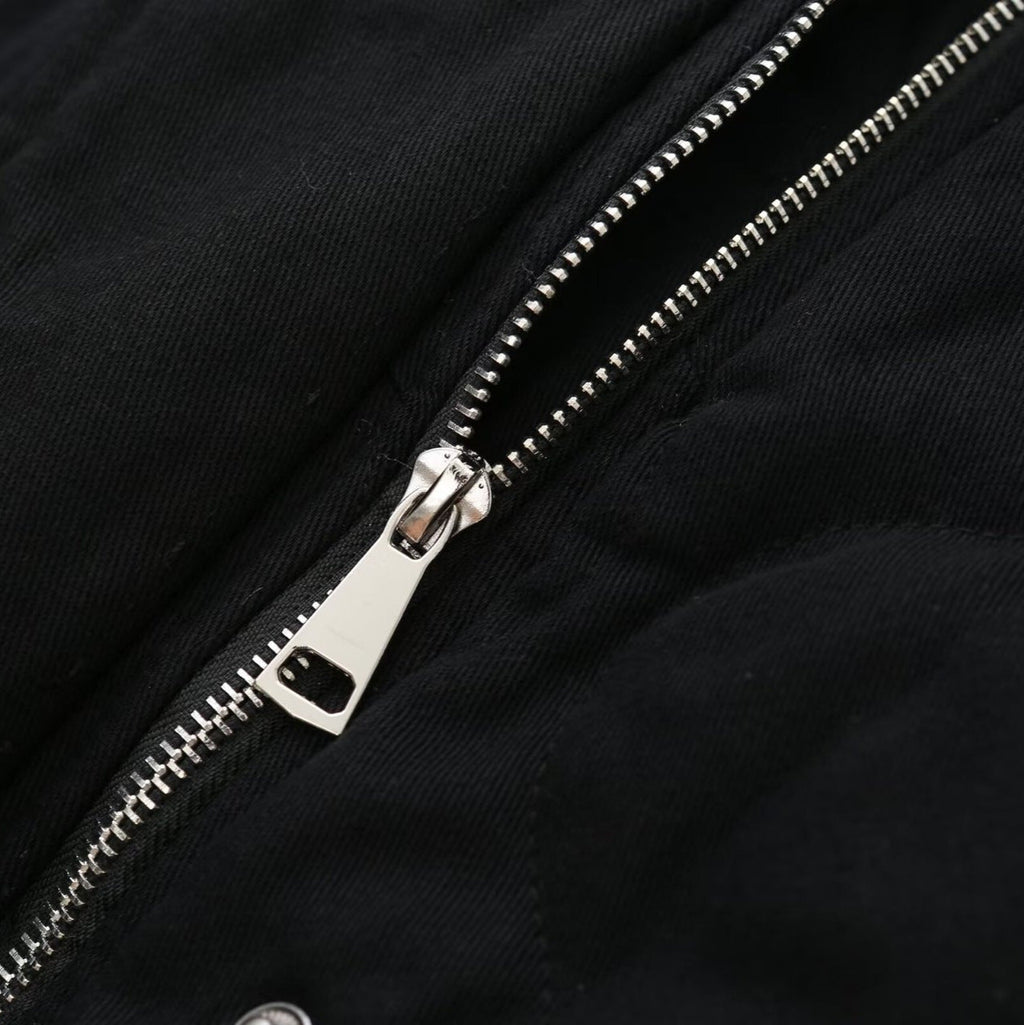 Gros plan sur une fermeture éclair métallique argentée sur une veste noire en tissu épais. Mode, vêtement, détail, textile, style urbain.
